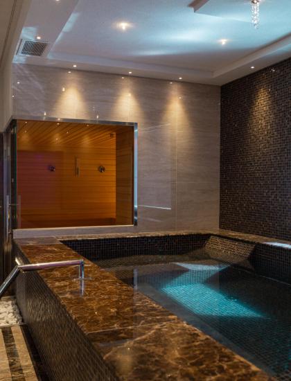Innenpool mit Sauna, sanfter Beleuchtung und elegantem Design.