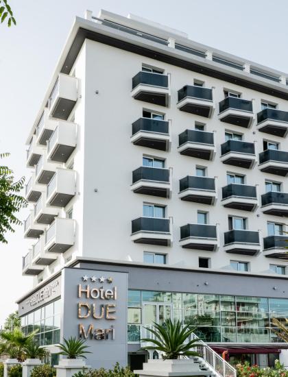 Modernes Hotel mit Balkonen, Glasfenstern und Palmen.