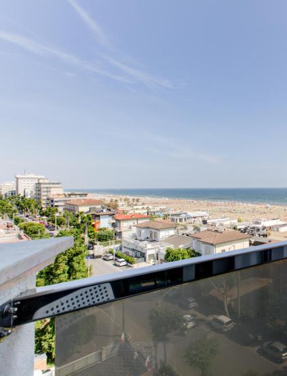 Vista mare da un balcone con sedie bianche.
