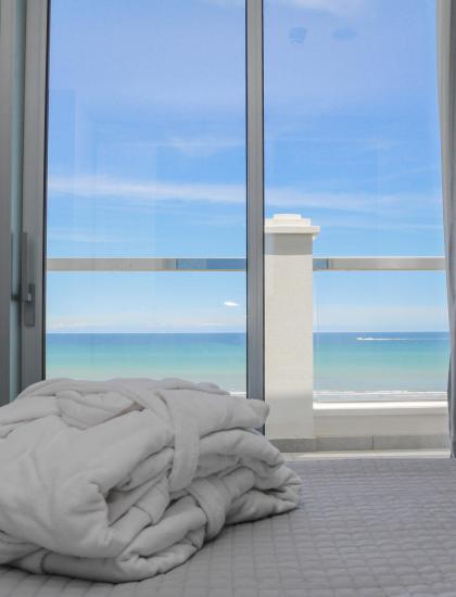 Camera con vista mare, accappatoio su letto, finestra grande.