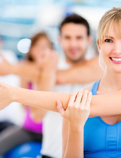 Menschen dehnen sich in einem Fitnessstudio und lächeln.