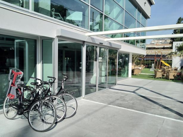 Biciclette parcheggiate fuori da un edificio moderno con sedie all'aperto.