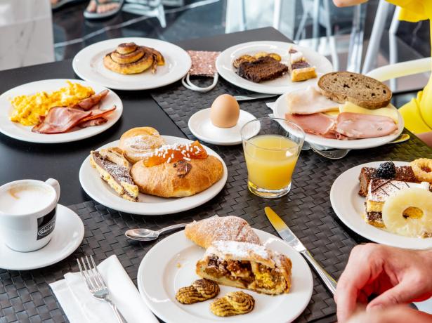 Colazione varia con dolci, uova, salumi e succo d'arancia.