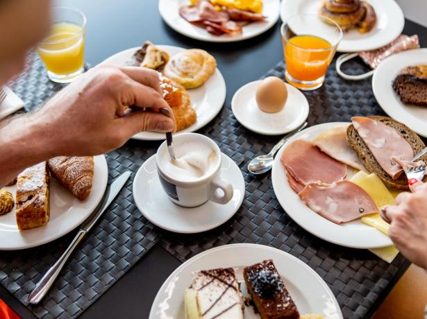 Colazione con caffè, succo d'arancia, pane, formaggi, salumi e dolci vari.