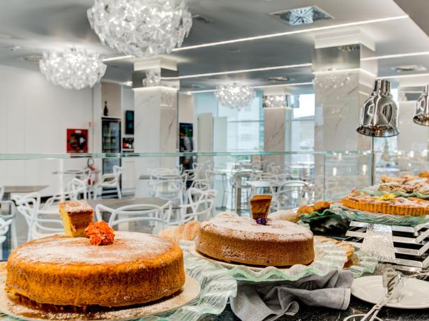 Dessert buffet in an elegant modern dining room with sparkling chandeliers.