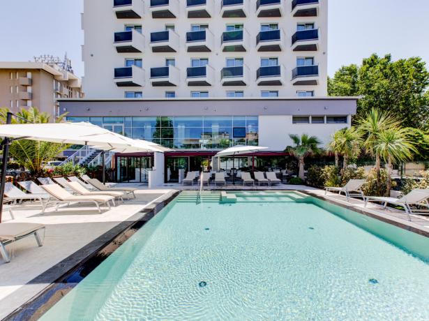 Outdoor pool with sun loungers and umbrellas, modern hotel.