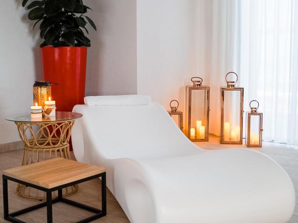 Relaxation room with white chair, candles, and plants.