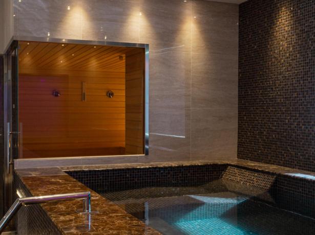 Innenpool mit Sauna, sanfter Beleuchtung und elegantem Design.