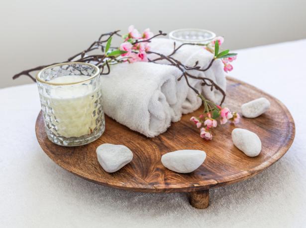 Tray with candles, towels, flowers, and stones for a relaxing ambiance.