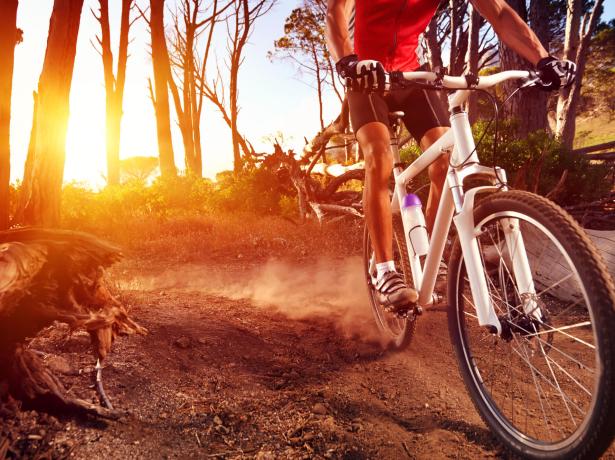 Ciclista su sentiero sterrato al tramonto.