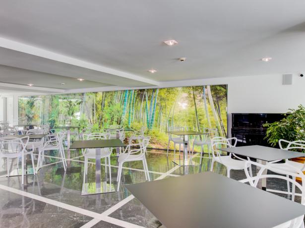 Sala moderna con sedie bianche e murale di foresta.