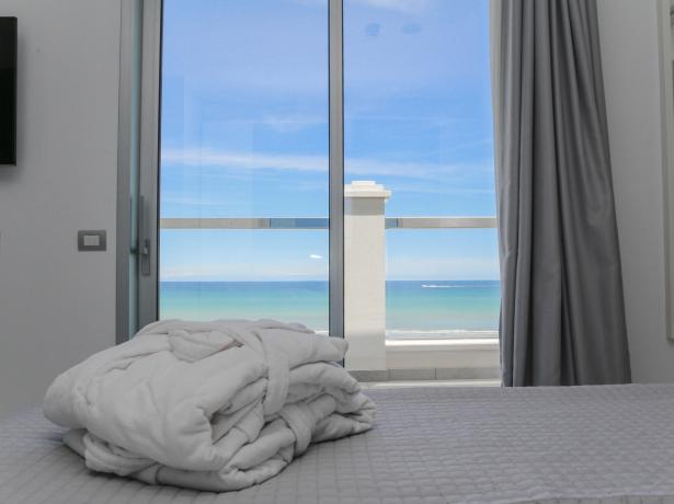 Camera con vista mare, accappatoio su letto, finestra grande.
