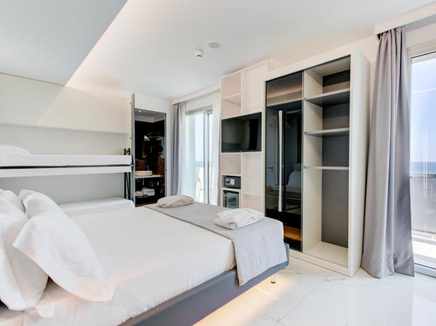 Modern room with double bed, bunk bed, and sea view.
