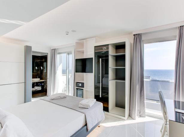 Camera moderna con vista mare, letto matrimoniale e scrivania.