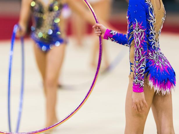 Gymnasts with hoops, wearing colorful and sparkling costumes.