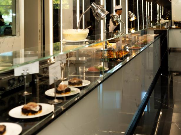 Elegantes Buffet mit Gourmetgerichten und Koch in moderner Küche.