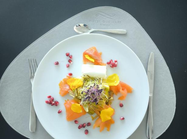 Piatto elegante con salmone, germogli e melograno.