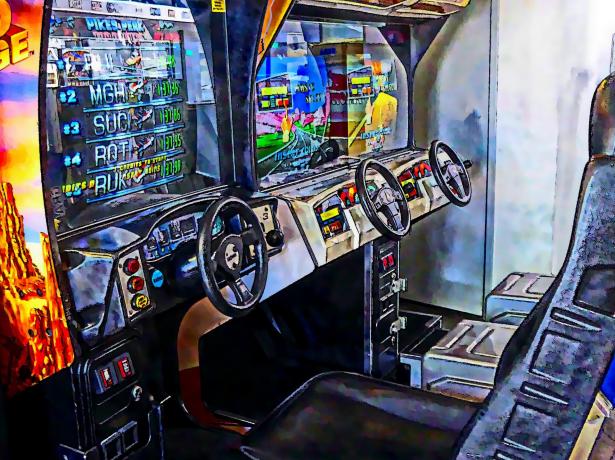 Arcade driving cabin with two steering wheels and screens.
